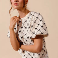 Ivory woven bubble sleeve top with black bow texture pattern and cropped shoulder detail