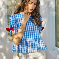 Blue gingham short-sleeve peplum blouse with red bow ties and gathered waist detail