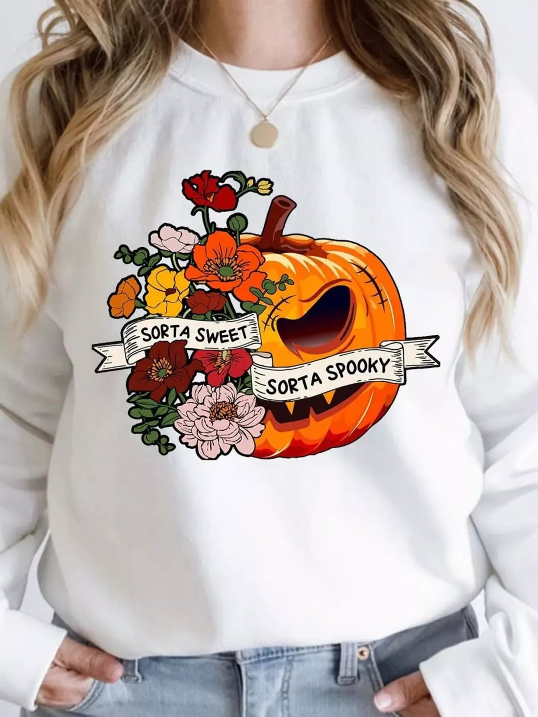 White crewneck sweatshirt with orange pumpkin graphic and flower accents