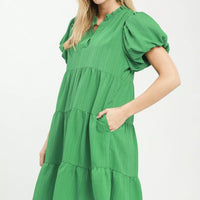 Green tiered babydoll dress with gathered bodice and puff sleeves