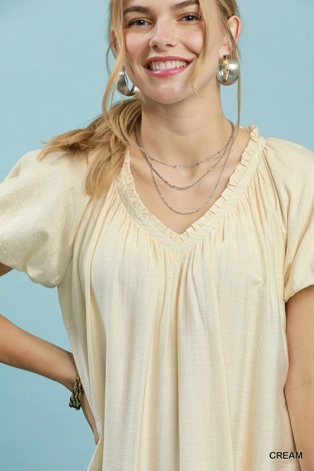 Cream mini shift dress close-up with V-neck ruffles and short puff sleeves.