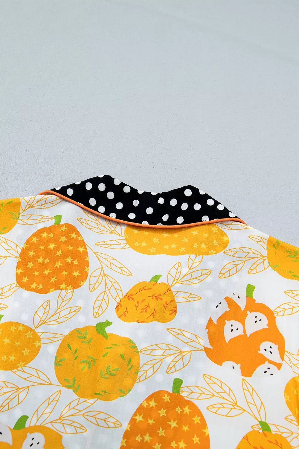 Close-up of pumpkin print fabric with black polka-dot collar trim