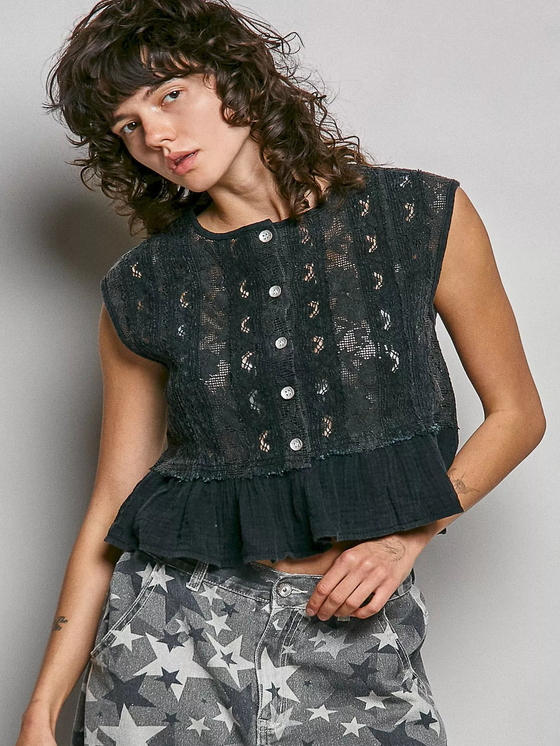 Black lace sleeveless top with round neck and button placket, ruffled peplum hem
