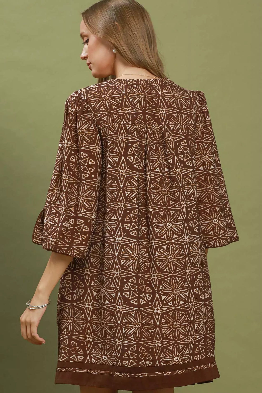 Brown geometric print tunic dress, back view with flared sleeves and patterned hem