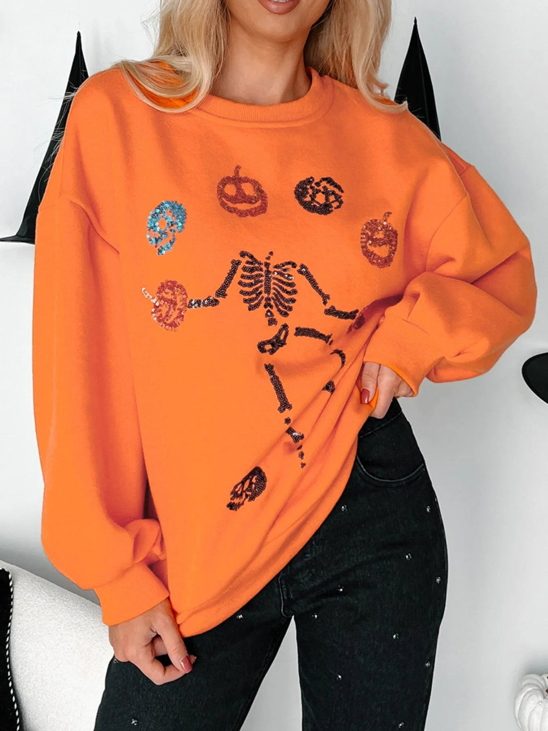 Orange crewneck sweatshirt with Halloween skeleton and pumpkin graphic