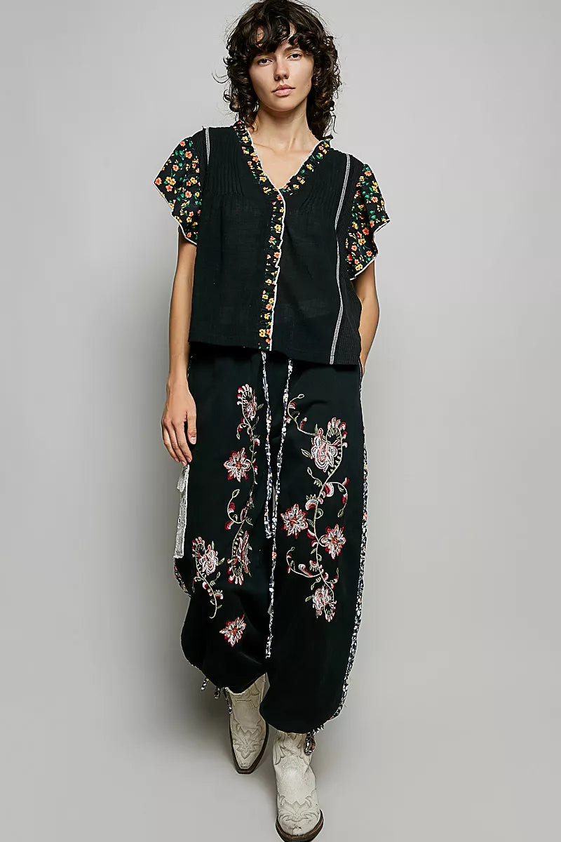 Black ruffle-sleeve blouse with floral V-neck trim and vertical contrast piping
