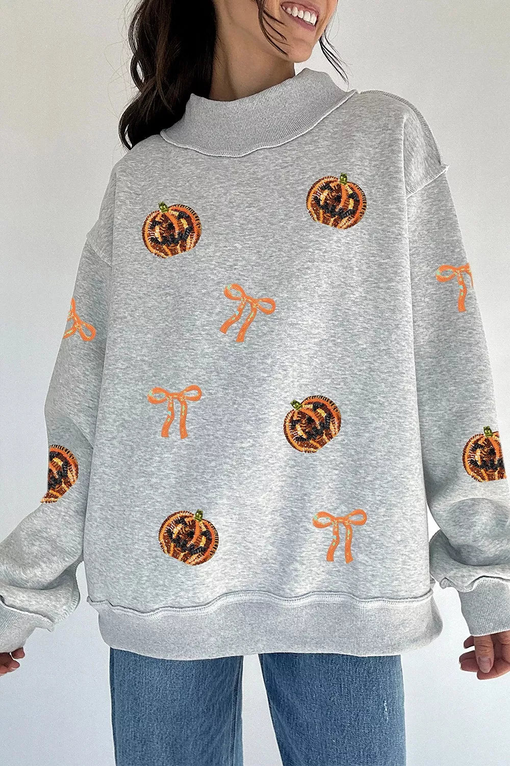 Light gray Halloween sweatshirt with orange sequin pumpkin face and bow patterns