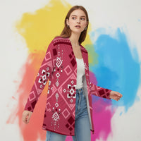 Woman wearing a pink patterned cardigan against a colorful abstract background