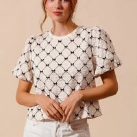 Ivory woven bubble sleeve top with black bow texture pattern and crew neckline