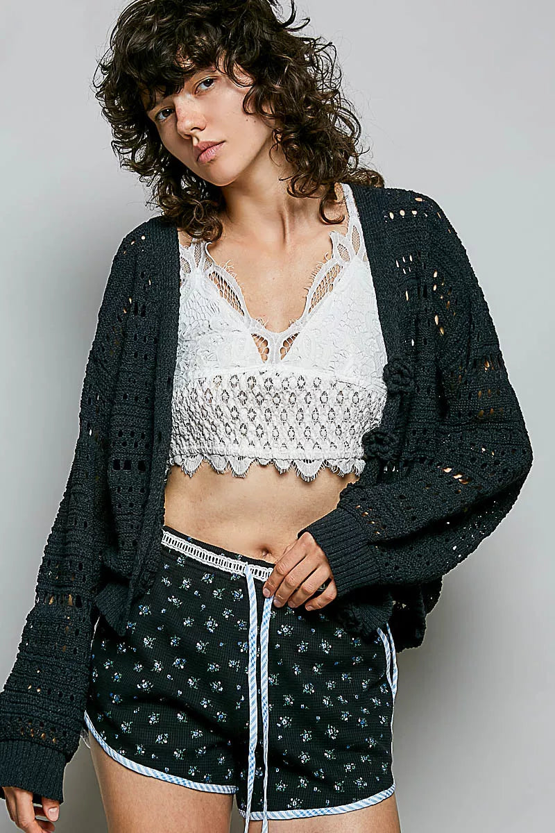 Black open-knit button cardigan worn open, long sleeves, crochet hole pattern