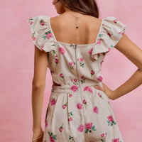 Ivory floral romper with open back and ruffled cap sleeves, pink rose print