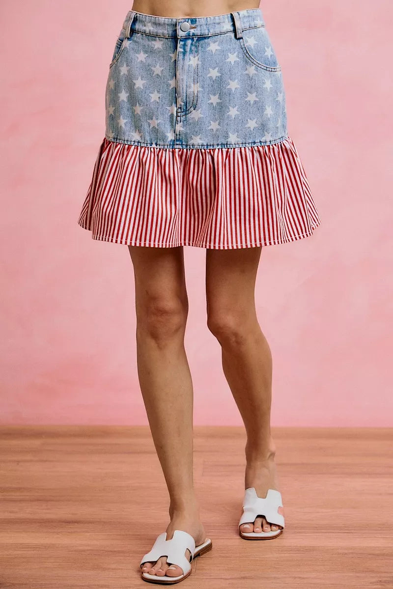 Blue denim mini skirt with star print top panel and red-and-white striped ruffle hem.