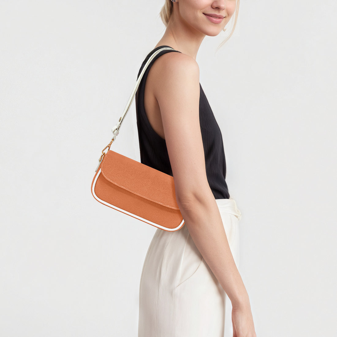 Orange flap shoulder bag worn sideways with gold chain strap and white trim