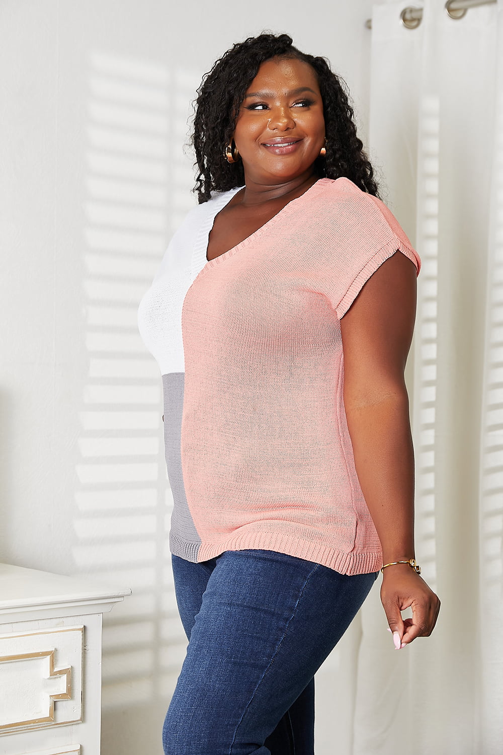 Color-block V-neck knit top in pink with white and gray panels, short sleeves.
