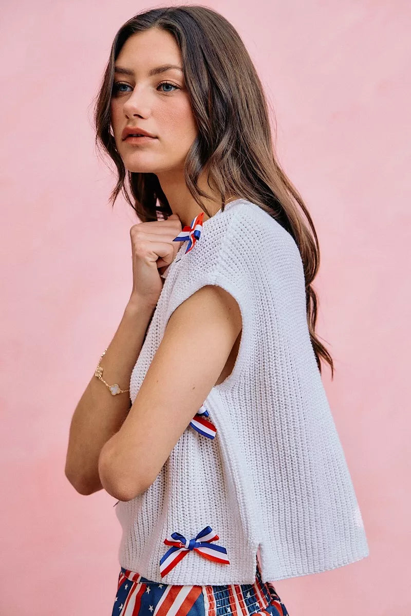 Off-white knit dolman sweater top with bow applique details on the sleeve and side