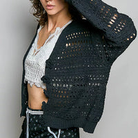 Black open-knit button cardigan draped over shoulders, long sleeves, crochet texture