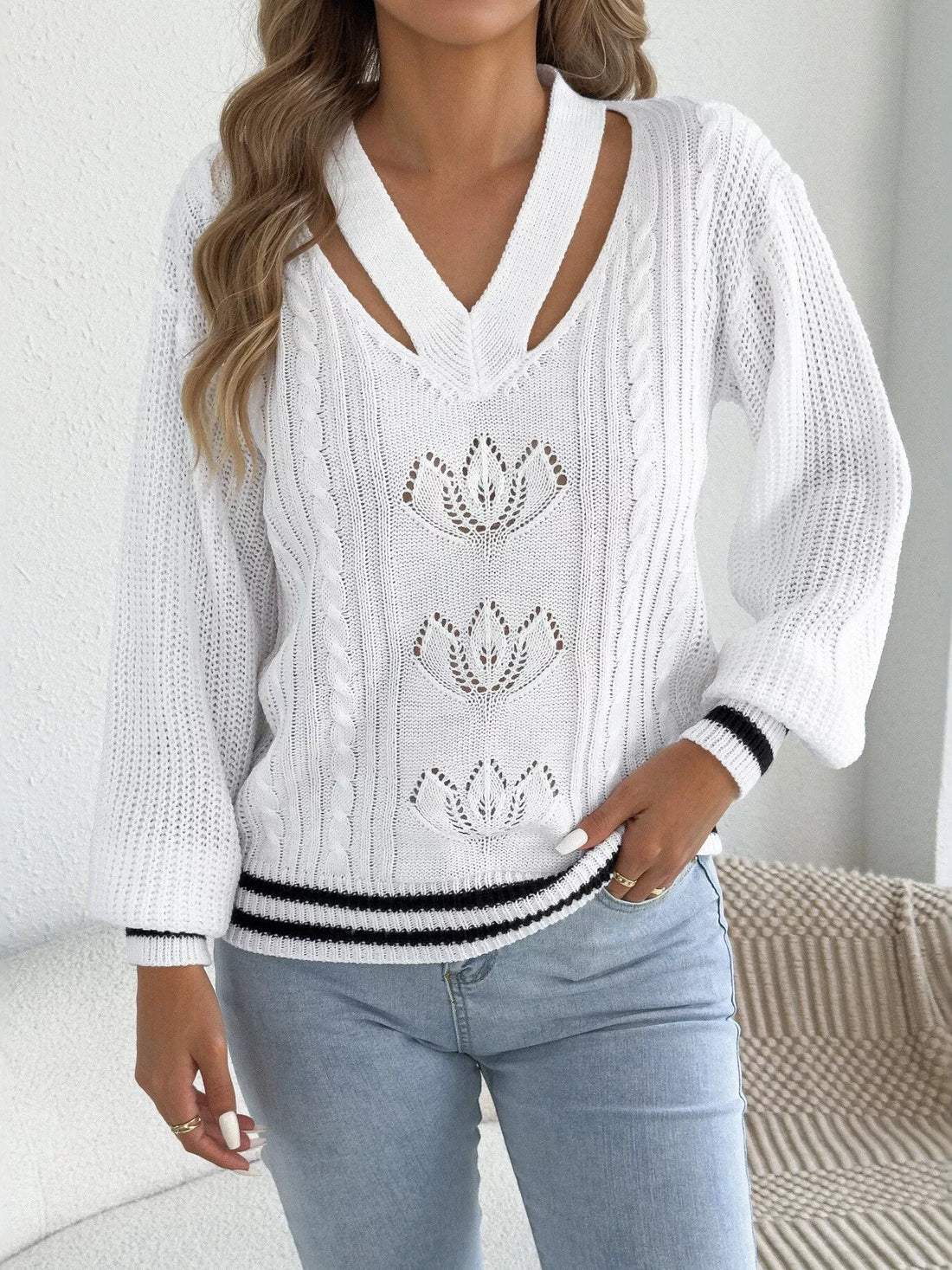 White V-neck cutout cable knit sweater with knit floral motifs and striped hem
