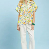 Green watercolor floral peasant blouse with V-neck and short sleeves, worn with white pants