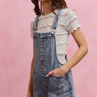 Light wash denim overall romper with adjustable straps, front buttons, and side patch pocket