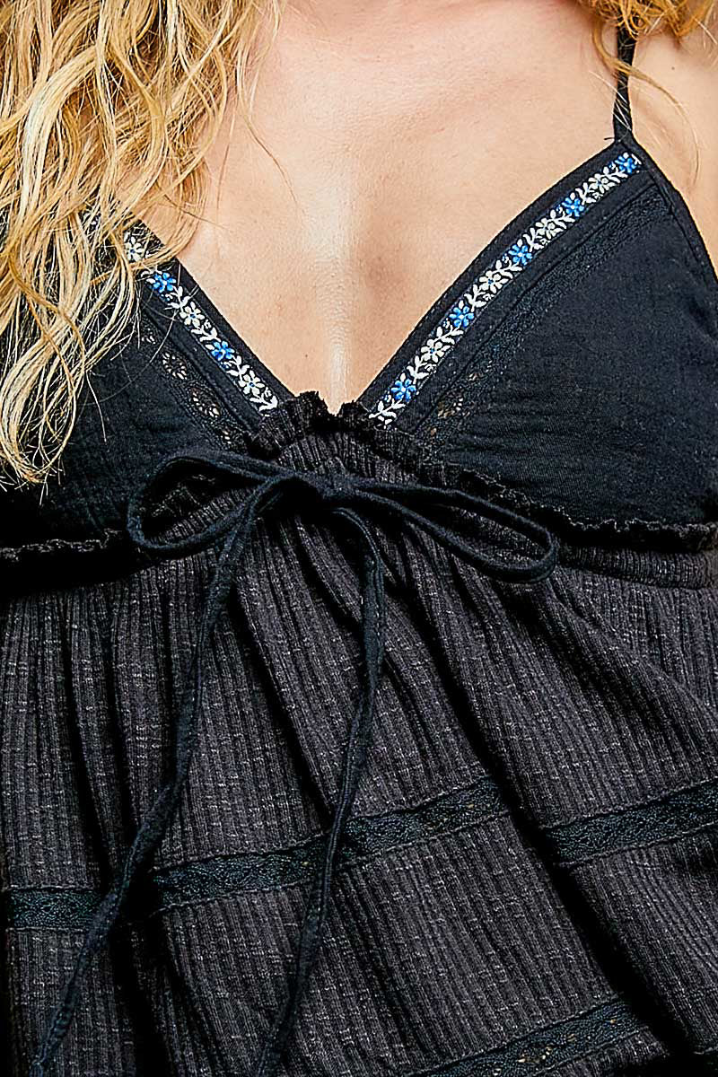 Close-up black cami neckline with embroidered trim and bow-tied front