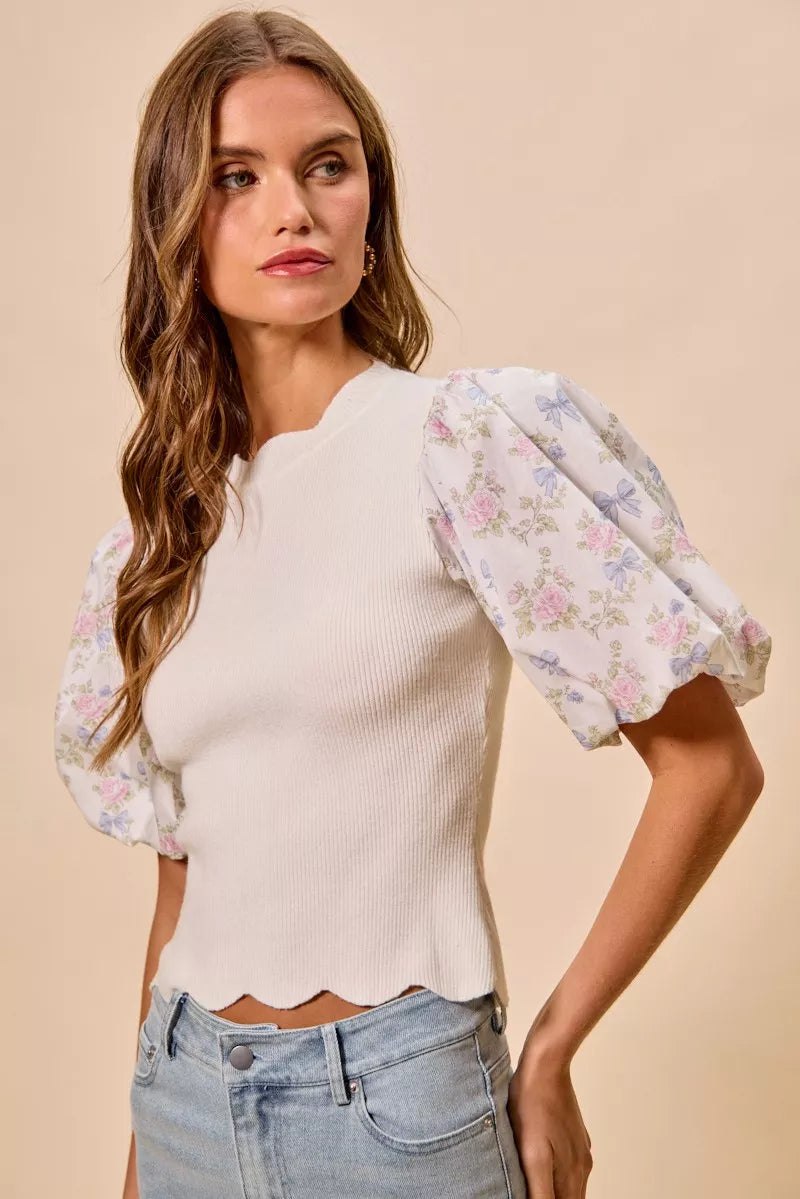 White ribbed knit sweater top with floral contrast puff sleeves and scalloped hem