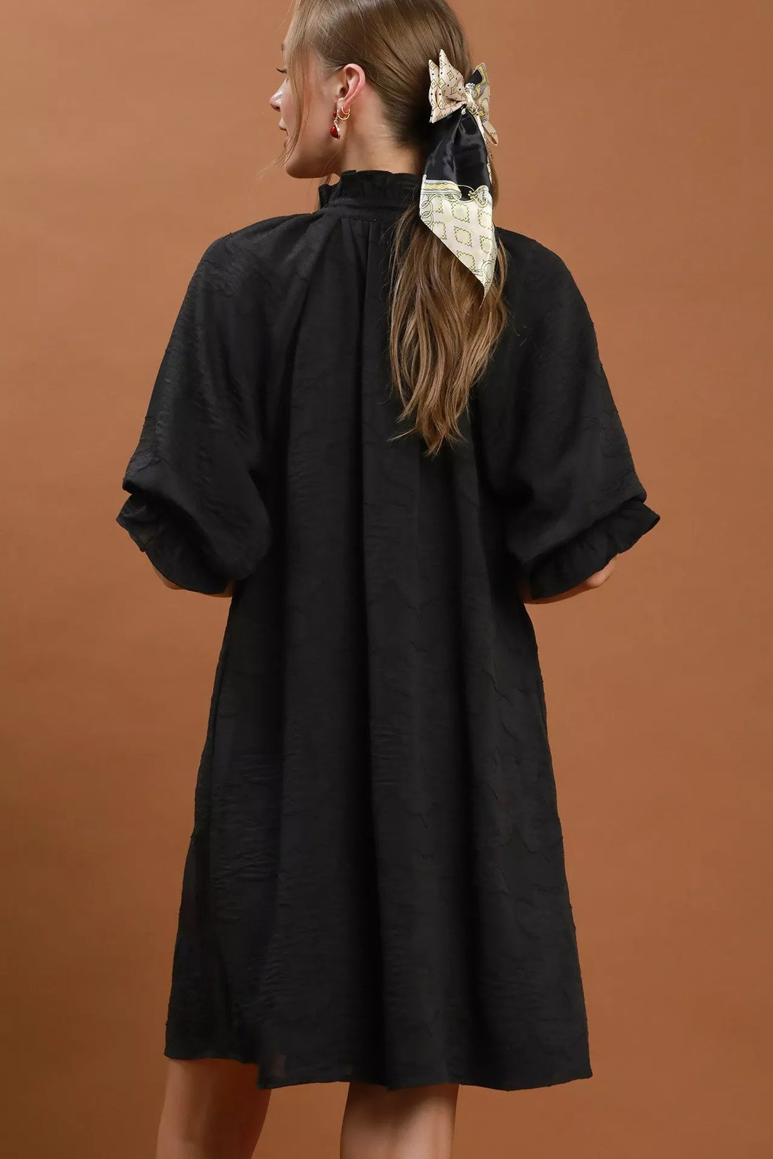 Black textured V-neck dress from back view with short flutter sleeves
