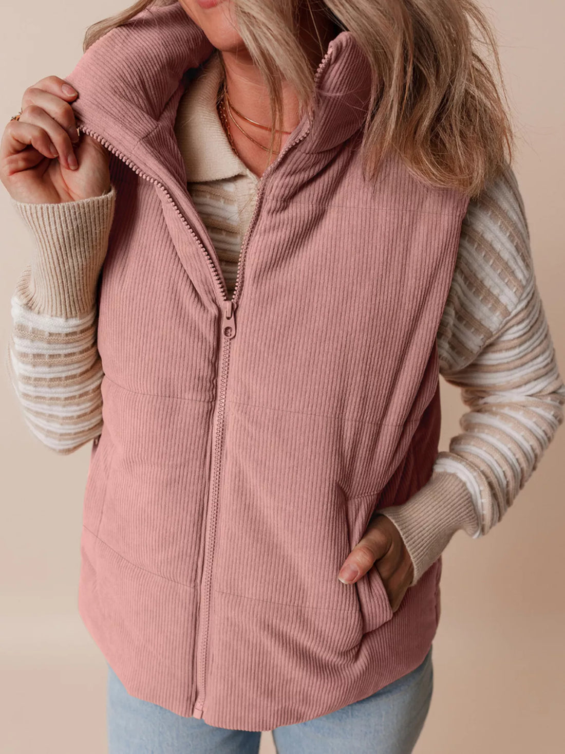 Dusty pink corduroy puffer vest with stand collar, zip front, and layered pocket detail.