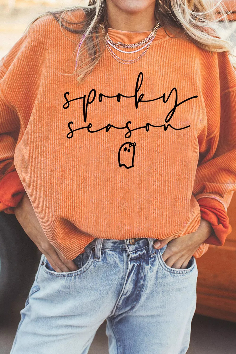 Orange ribbed sweatshirt close-up with “sprooky season” graphic and small ghost