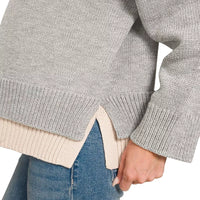 Grey sweater hem with beige ribbed contrast and slit detail, long sleeve cuff