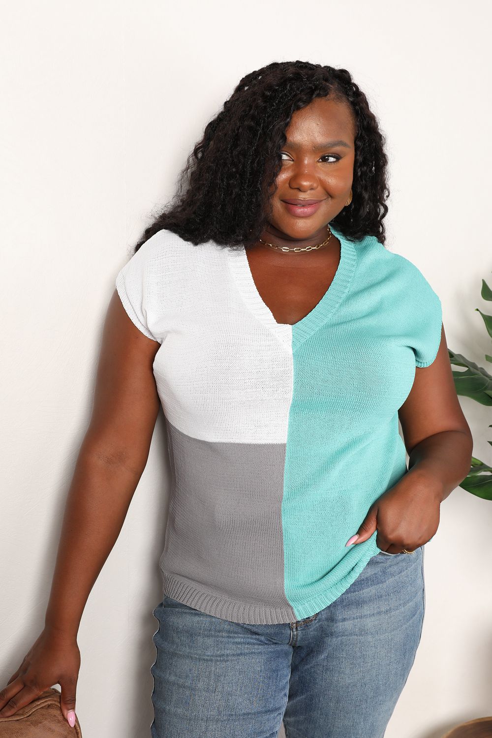 Model wearing turquoise and white color-block V-neck knit top with short sleeves.