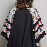Black knit top back view with floral ruffle sleeves and contrast chevron lace panel