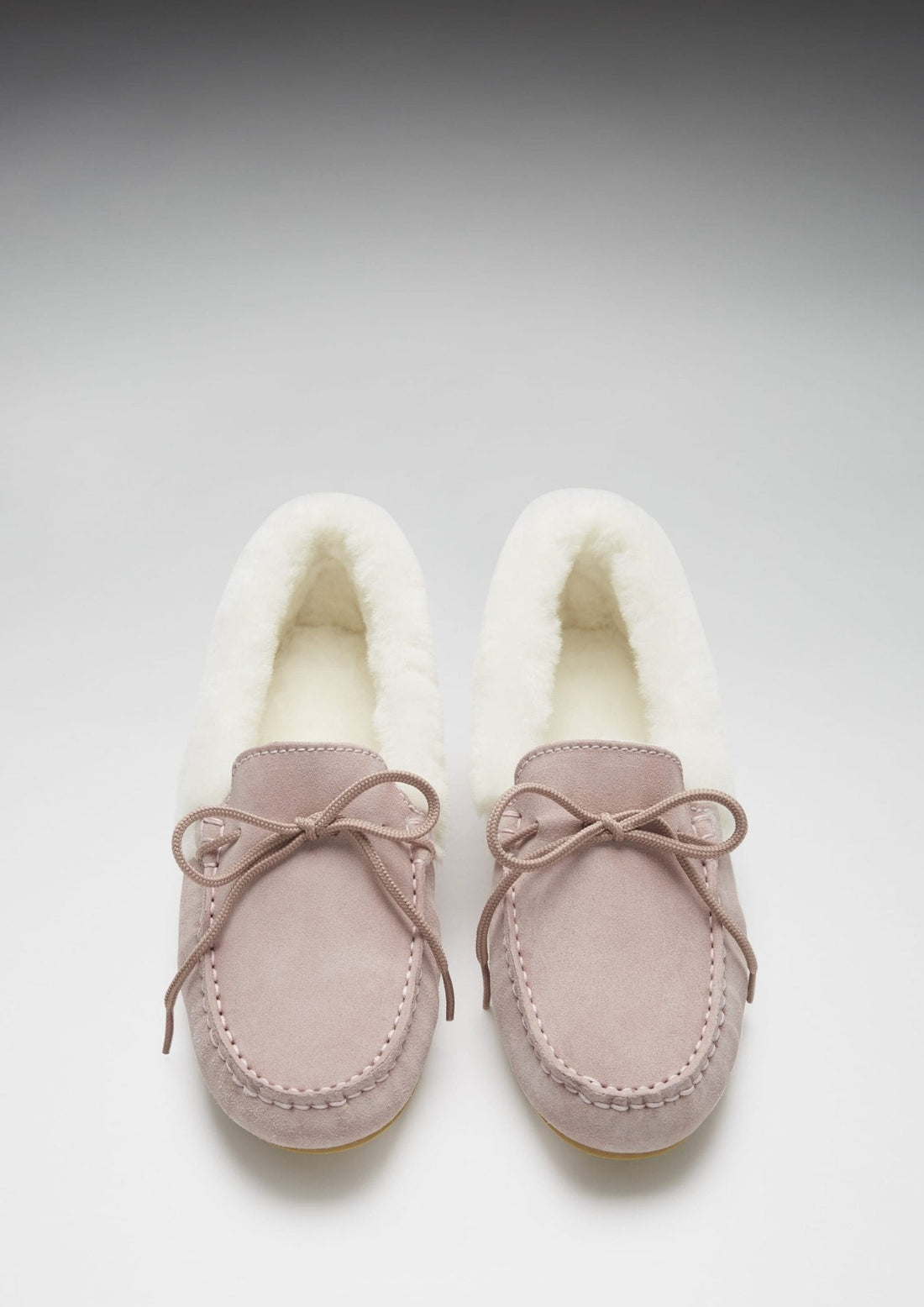 Front view of pink suede slippers with fleece lining and bow ties