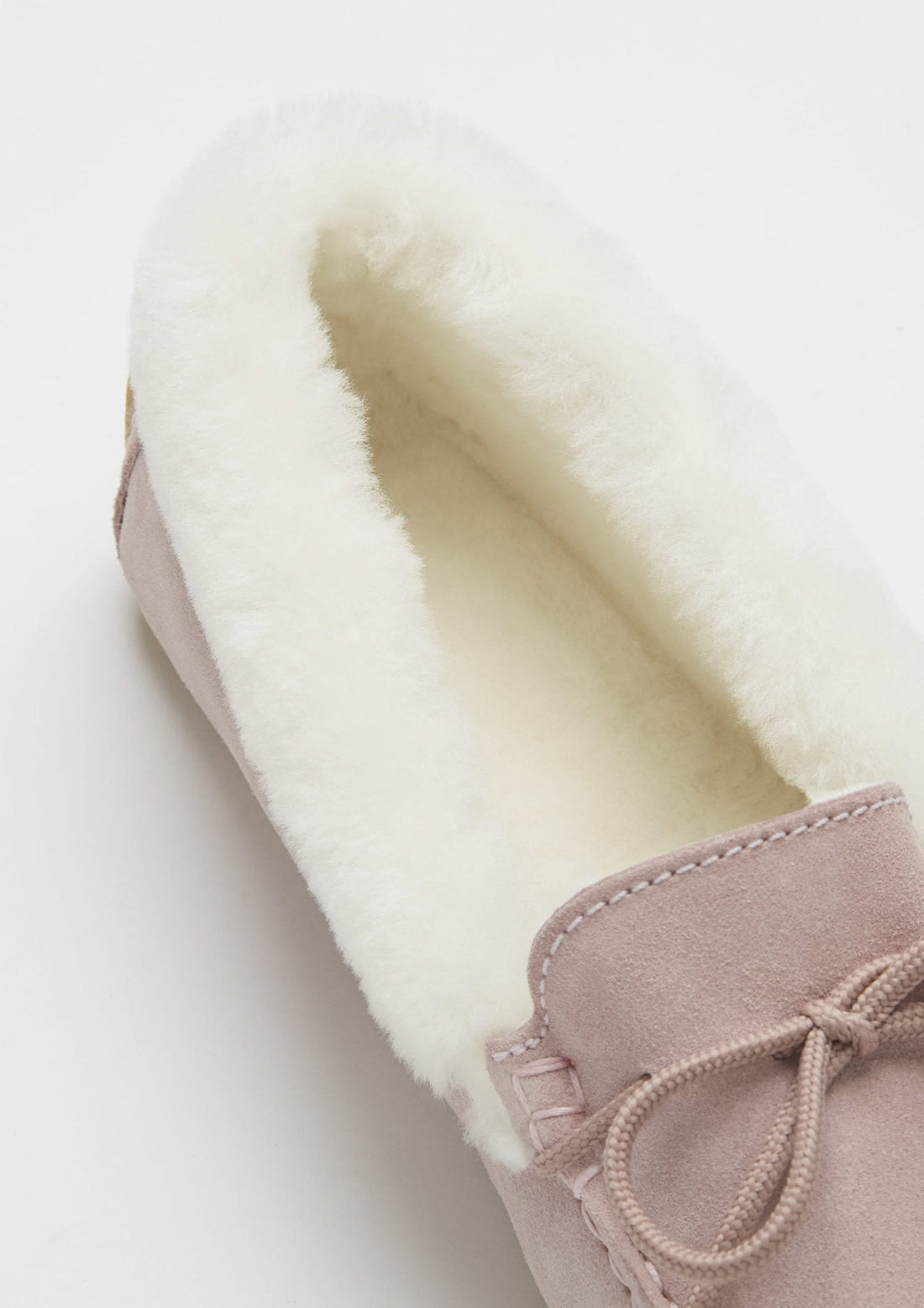 Close-up of the plush sheepskin lining inside a pink suede slipper