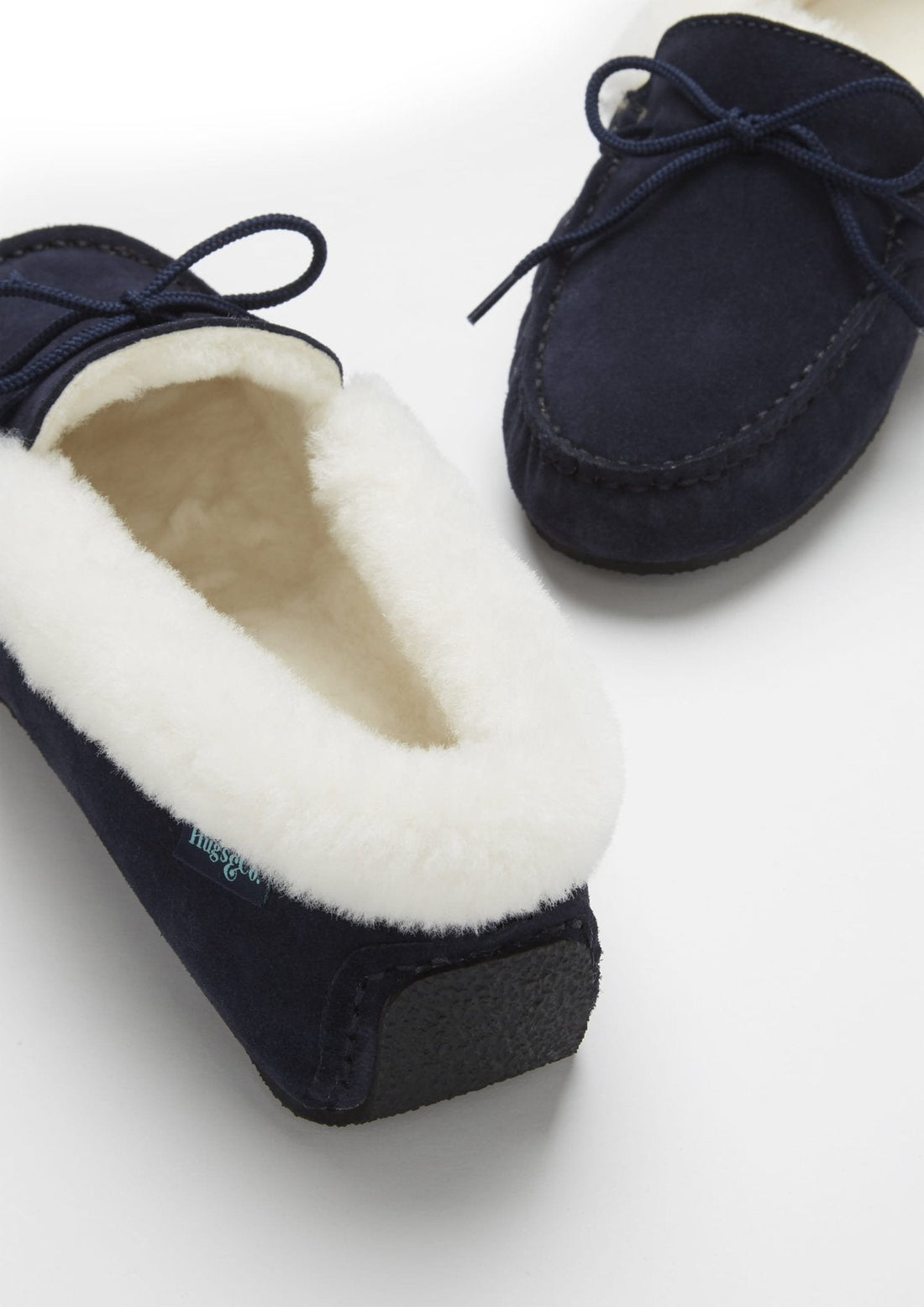 Navy suede slipper showing the plush lining, heel, and textured sole