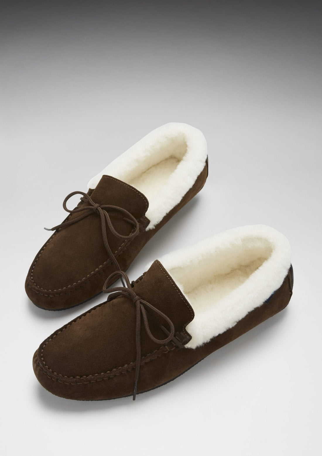 Pair of brown suede slippers with cream sheepskin lining and tied laces