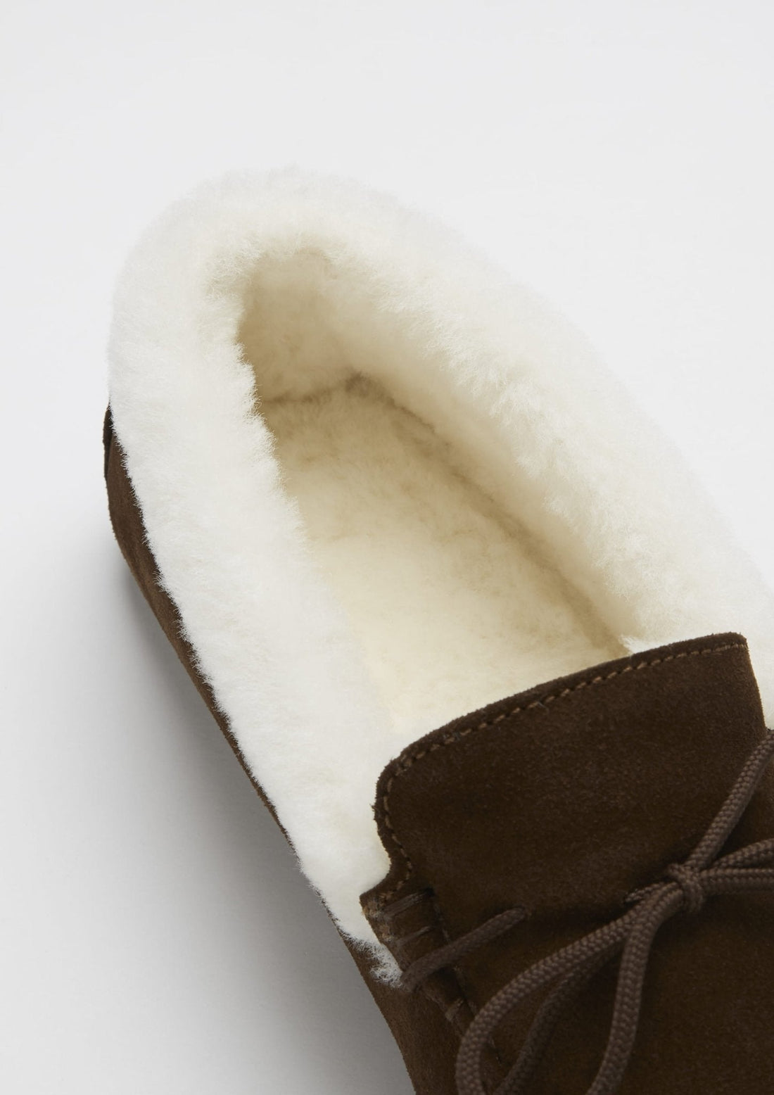 Close-up of the cream sheepskin lining and brown suede upper of a slipper