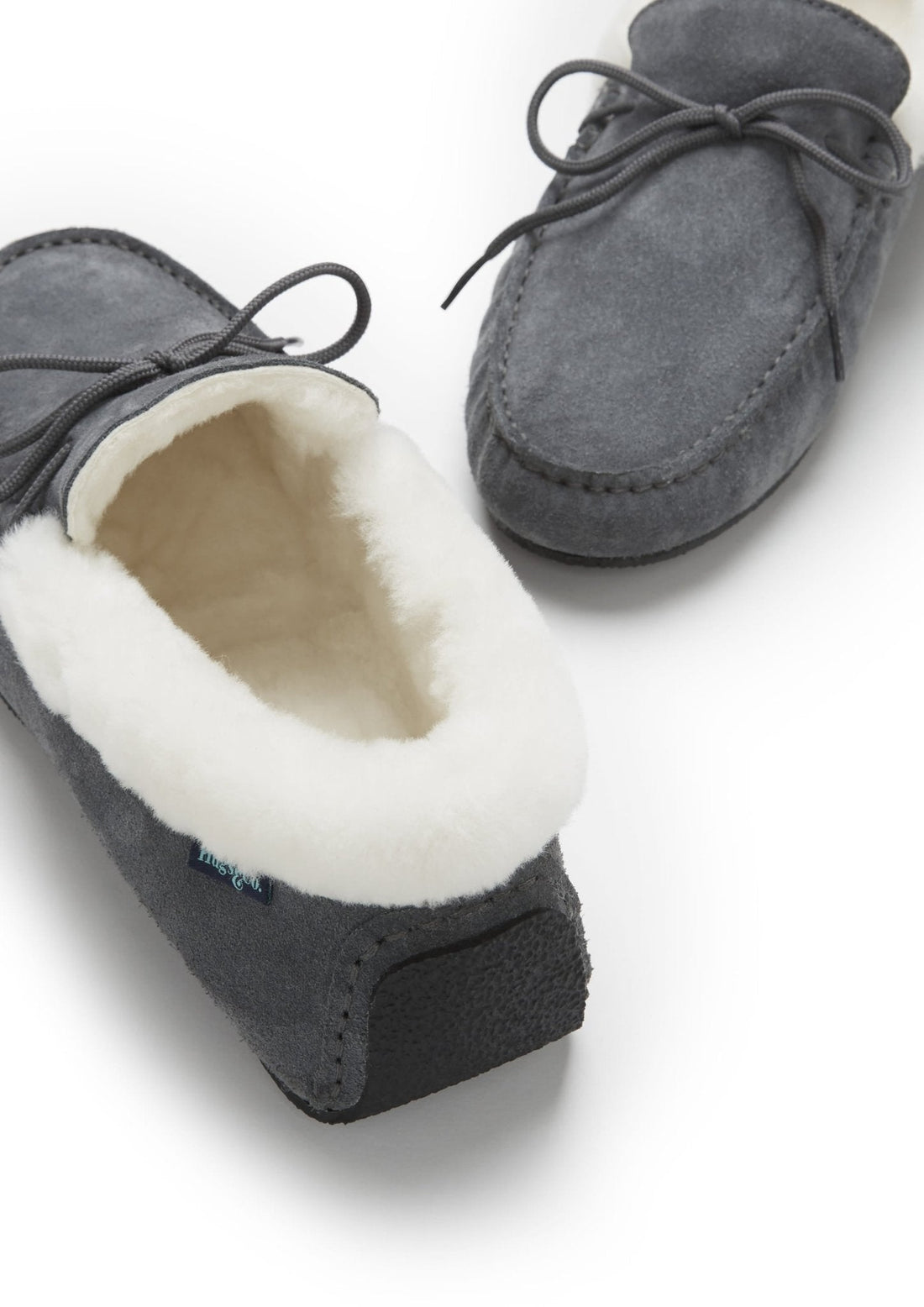 Slippers showing plush cream lining, suede uppers, and textured heel sole