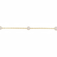 Close-up of gold chain bracelet with spaced round white pearls along the strand