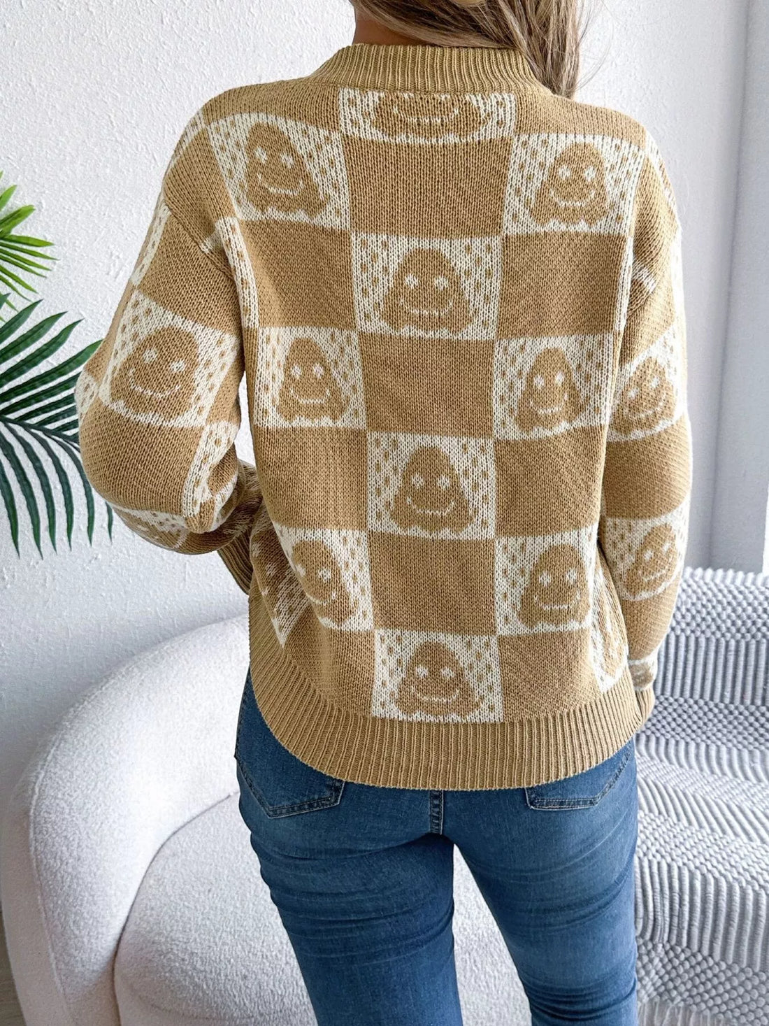Back view: beige checkerboard knit sweater with jack-o-lantern face pattern, long sleeves