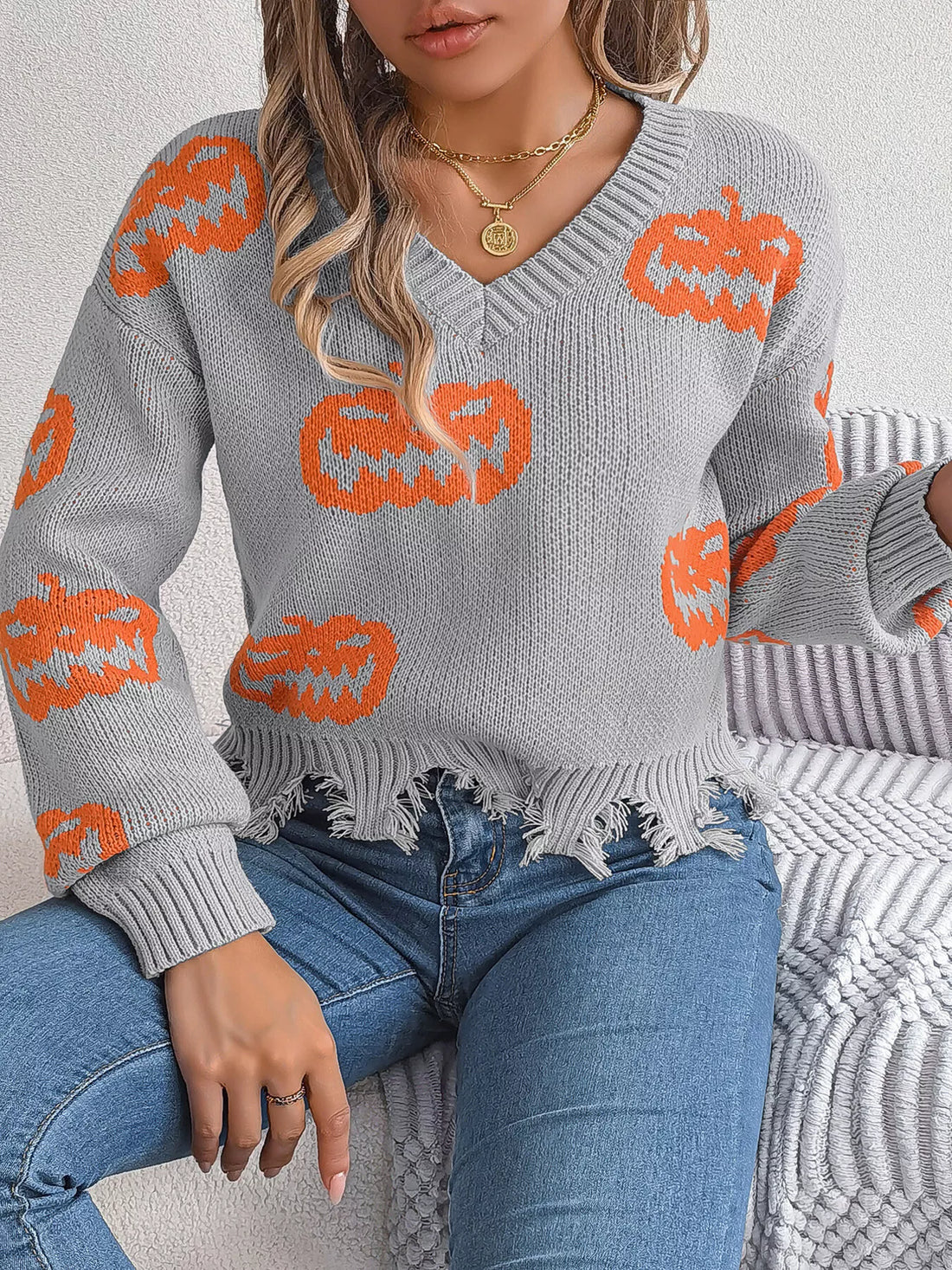 Gray V-neck pumpkin sweater with orange intarsia pattern and frayed, distressed hem