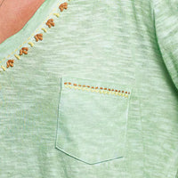Light green knit top close-up: embroidered neckline trim and chest pocket