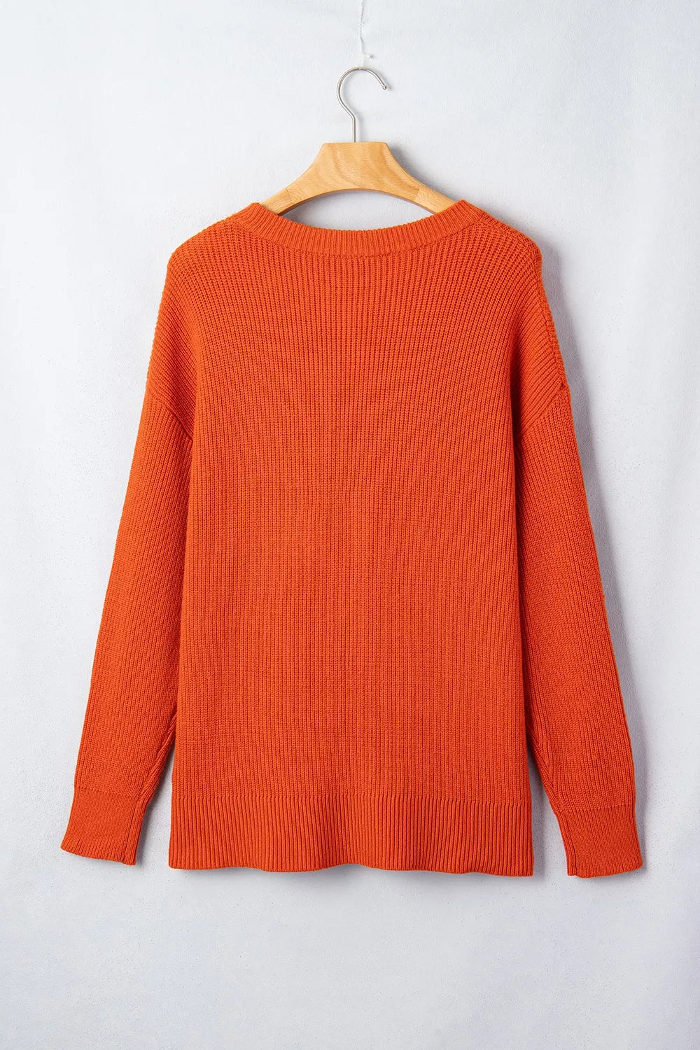 Orange knit sweater on hanger, crew neck, ribbed hem and cuffs, long sleeves