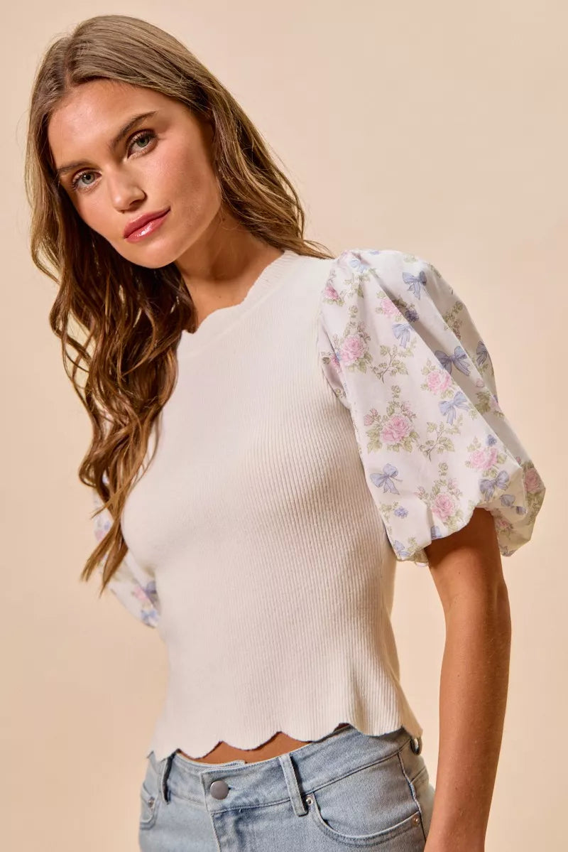 White ribbed sweater top with pastel floral puff sleeves and scalloped bottom edge