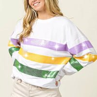 White pullover sweatshirt with wide sequin horizontal bands in purple, yellow, and green