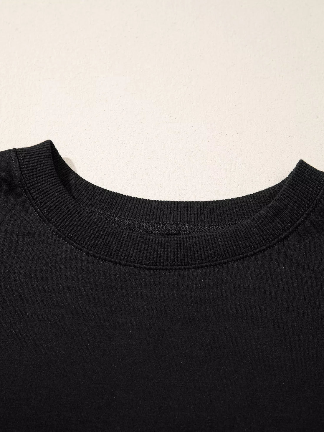 Black crewneck long-sleeve top with ribbed neckline detail