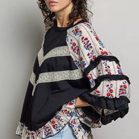 Black knit top with round neck, chevron lace yoke and floral ruffle-trim sleeves