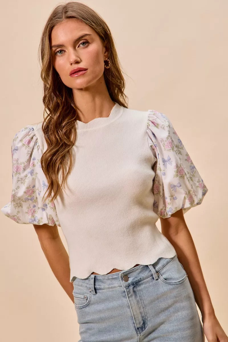 White knit sweater top with floral puff sleeves; scalloped bottom edge