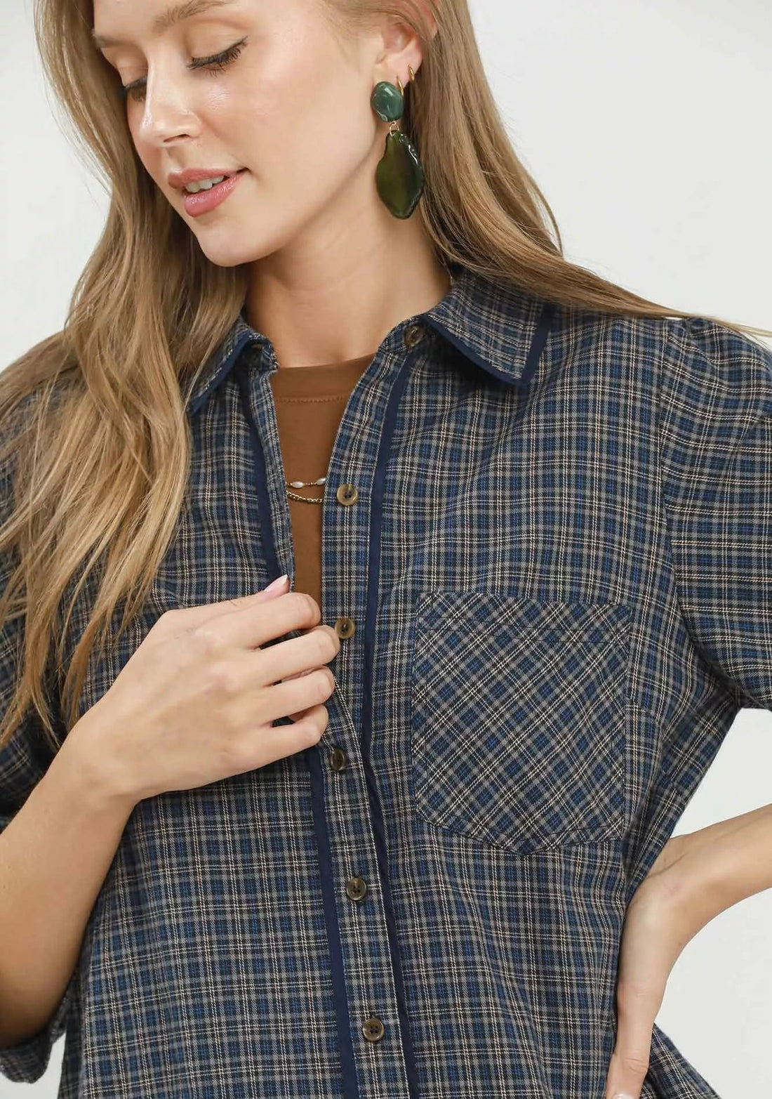 Close-up of navy plaid button-down shirt dress with chest pocket and gold buttons