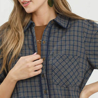 Close-up of navy plaid button-down shirt dress with chest pocket and gold buttons