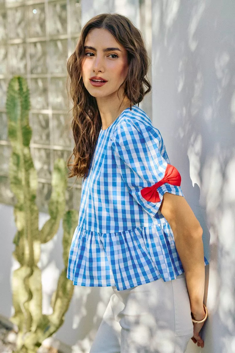 Blue gingham short-sleeve peplum blouse with red shoulder ribbon bows and gathered hem